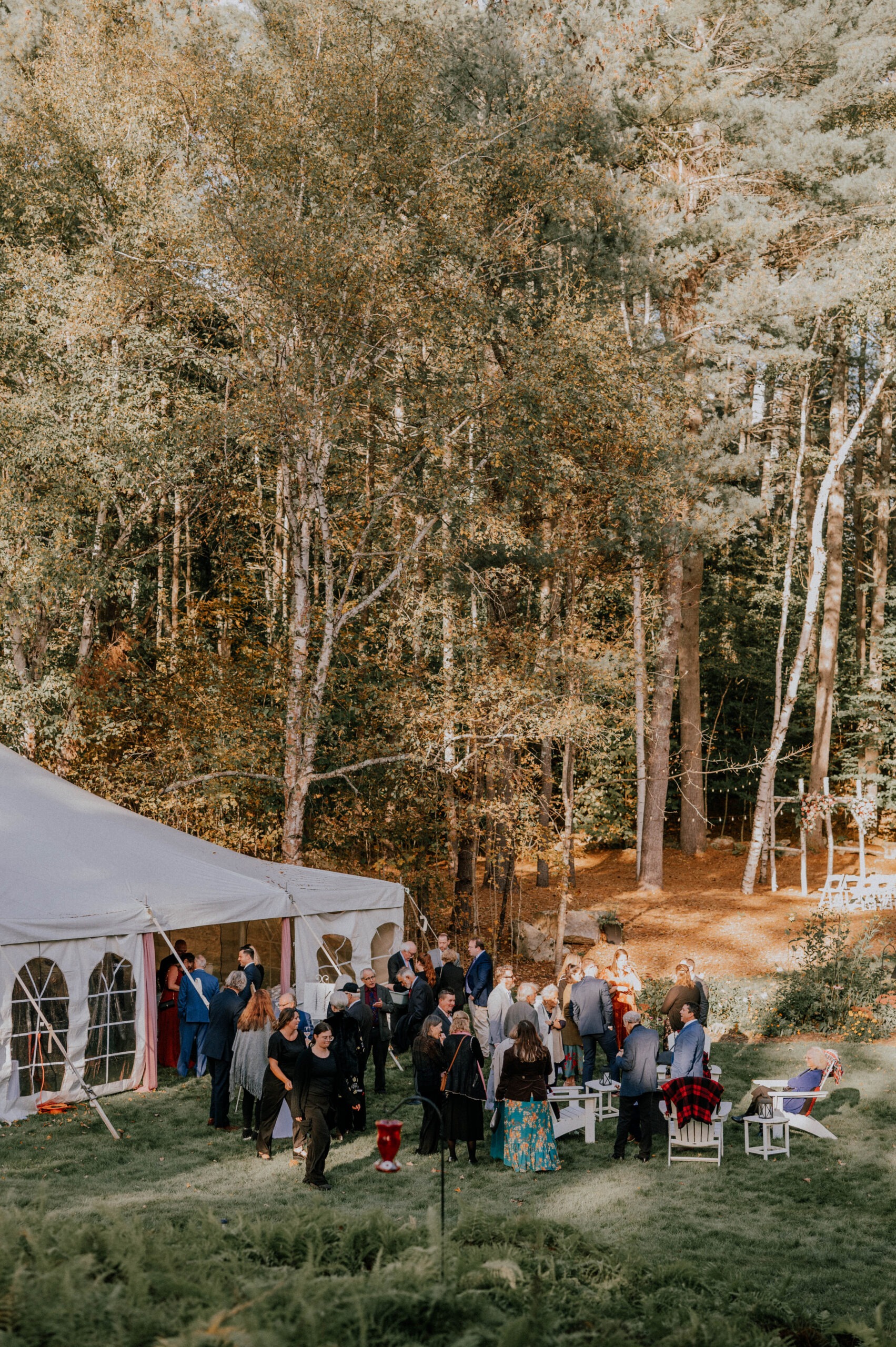 wedding ceremony under white tent surrounded by green trees