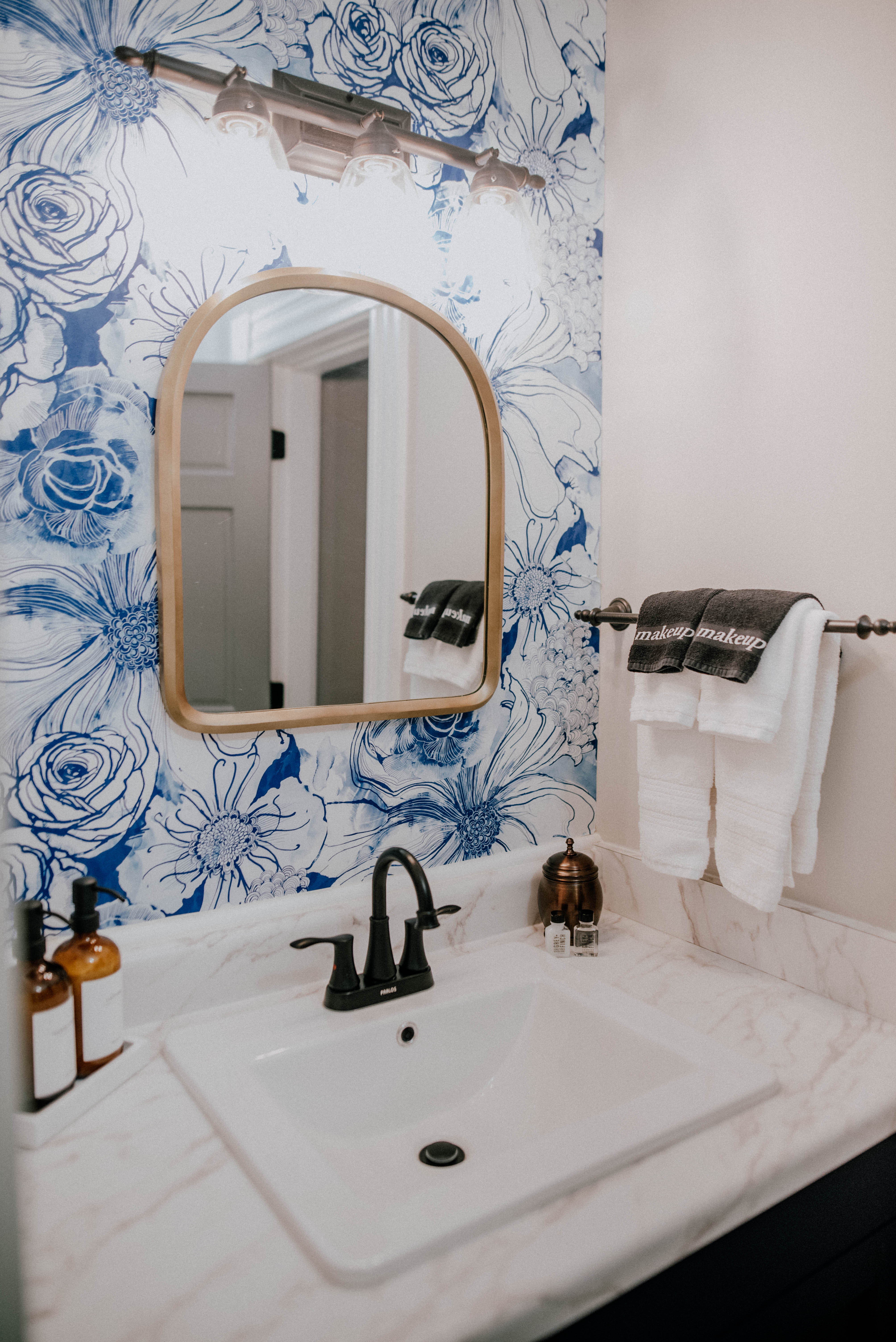 sink with gold mirror and blue and white floral wallpaper
