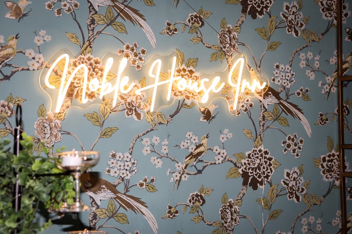 noble house inn neon sign on floral wallpaper