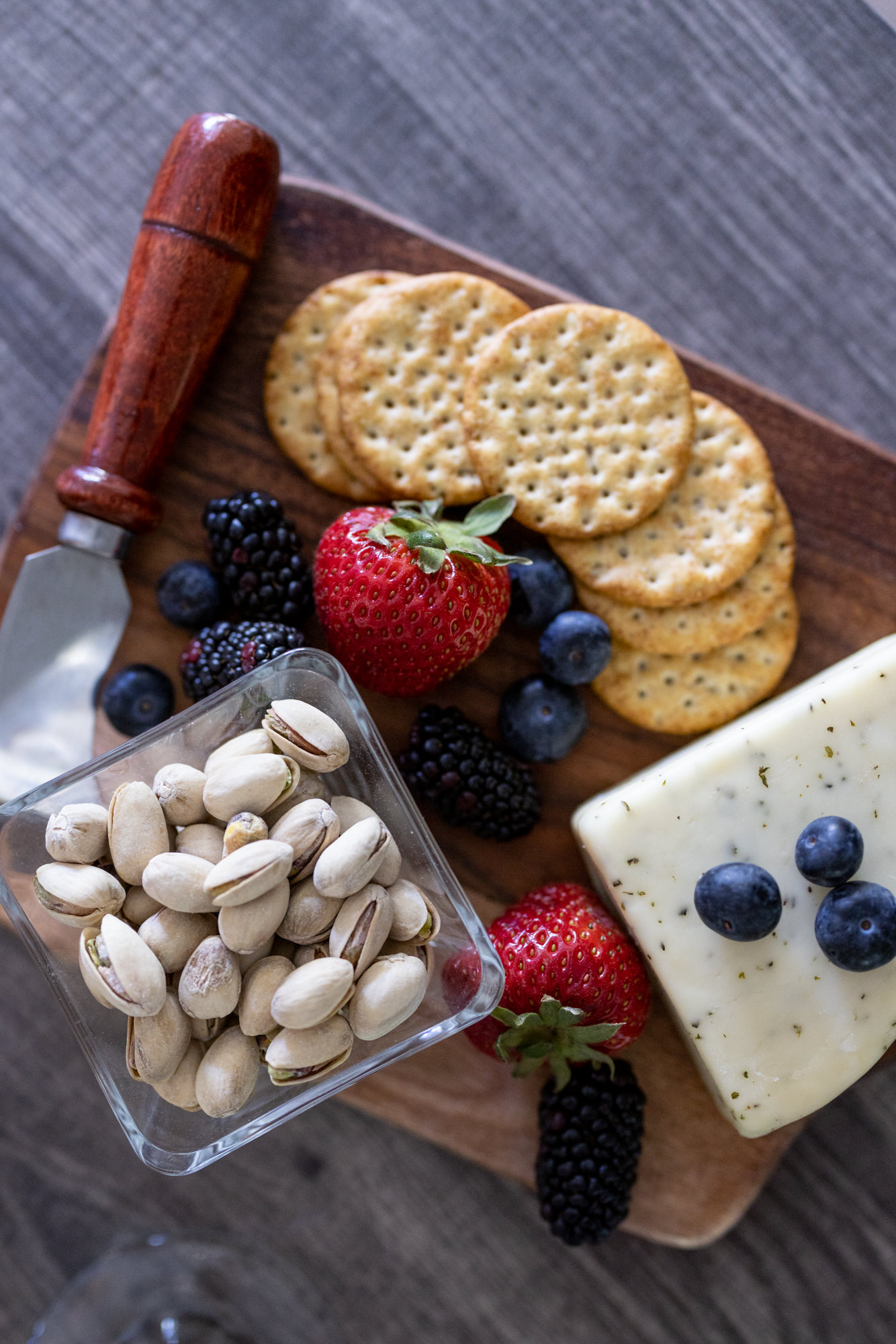 wooden platter with nuts, cheeses, and crackers