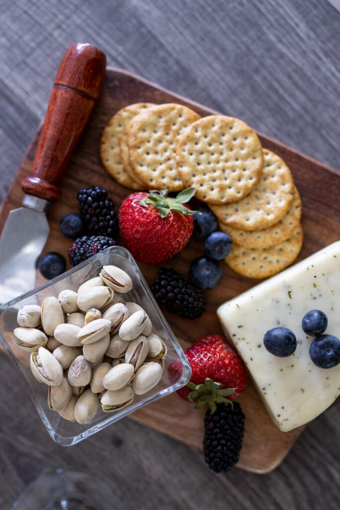 cheese, fruit, and crackers on a wooden board