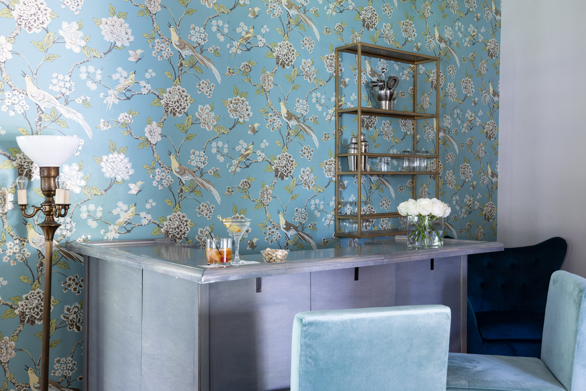 wet bar with blue floral wallpaper and velvet barstools